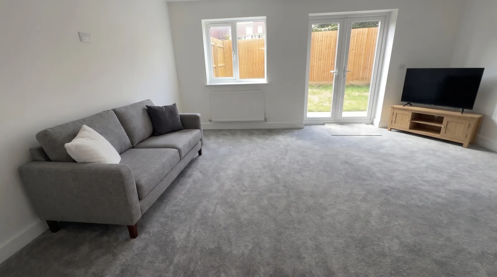 Stoke Lodge — the living room with a grey sofa and a 55-inch TV (illustrative furnishing)