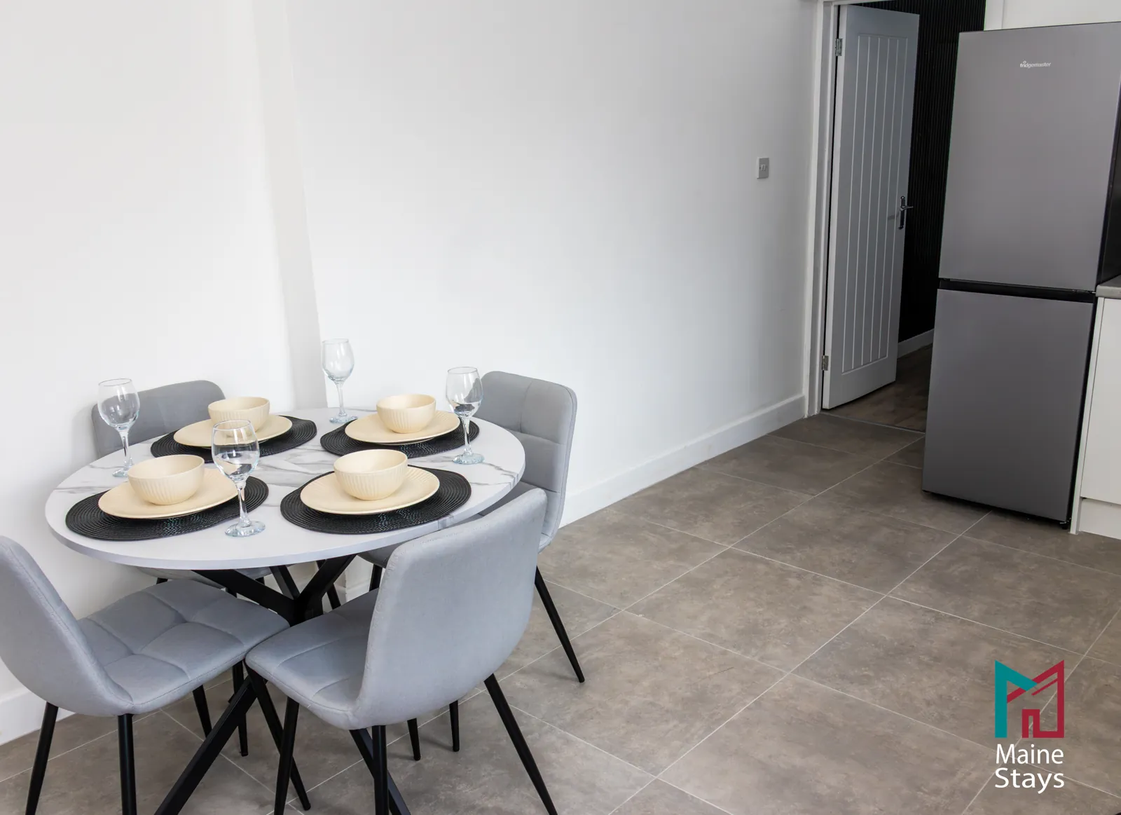 The Dudley Lounge — Round dining table for four beside the fridge freezer