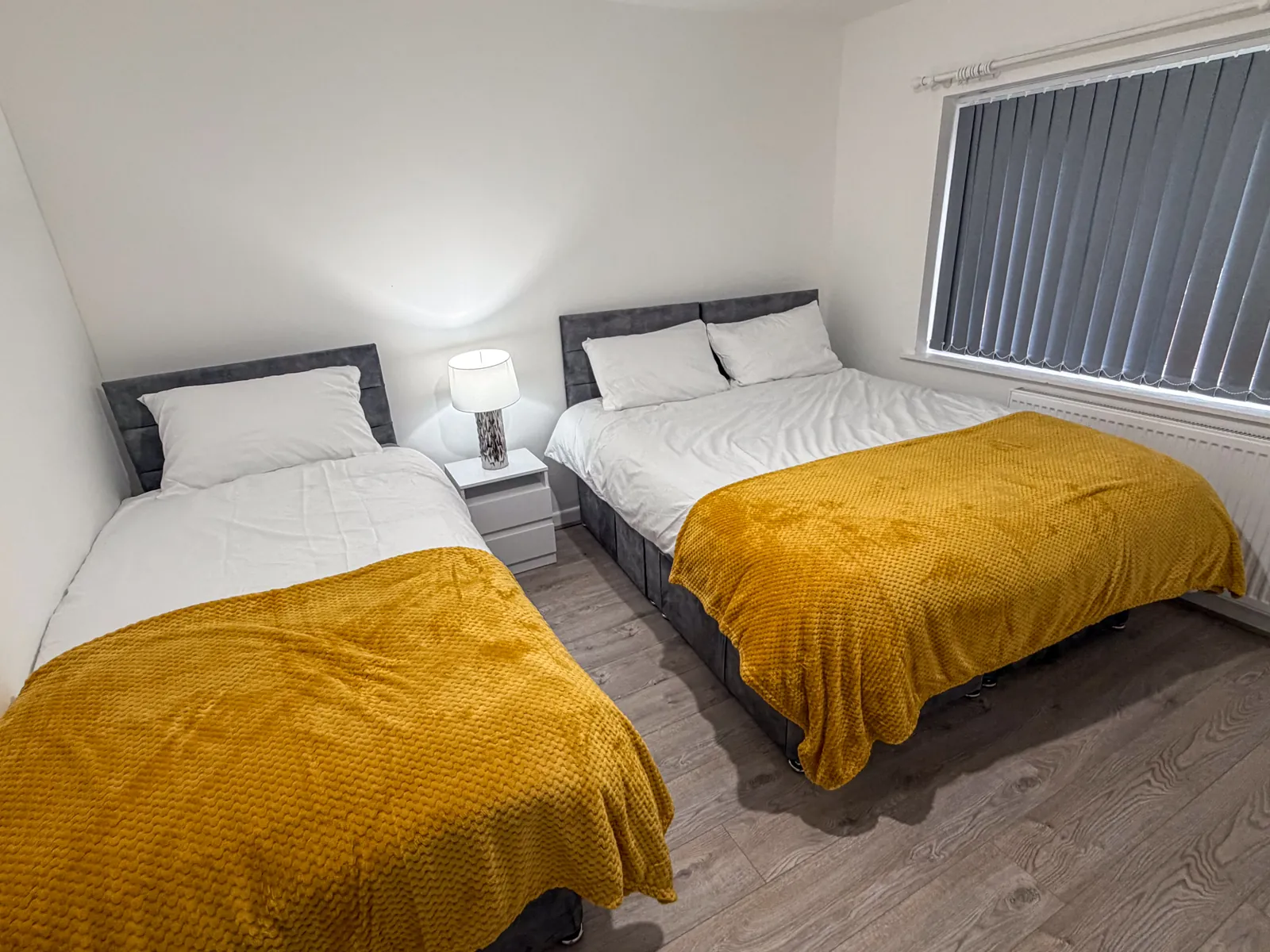 The Dudley Lounge — Bedroom with a double bed and a single bed with mustard throws